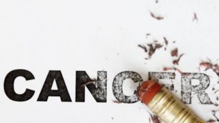 Pencil eraser erasing cancer text written on a white background