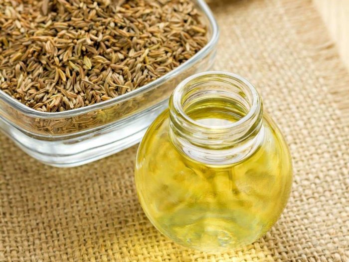 Cumin oil in a round jar with the seeds in another bowl a jute background