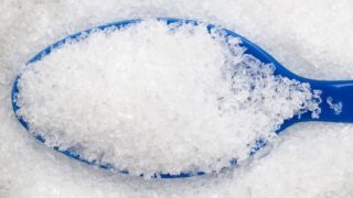 Closeup of a blue spoon in white crystallized powder.