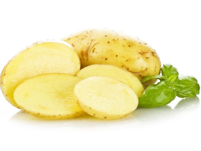 Sliced potato and a whole potato with a leaf beside