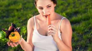 A pregnant woman eating salad or vegetables