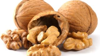 Peeled and unpeeled walnuts with a cream background