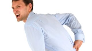 A young man suffering from backache standing on a white background