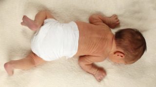 A baby wearing diapers sleeping on a clean white towel