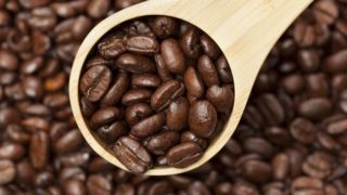 Coffee beans and a wooden spoon filled with the coffee beans