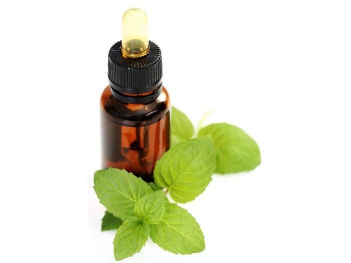 Peppermint oil bottle with fresh peppermint leaves on a white background