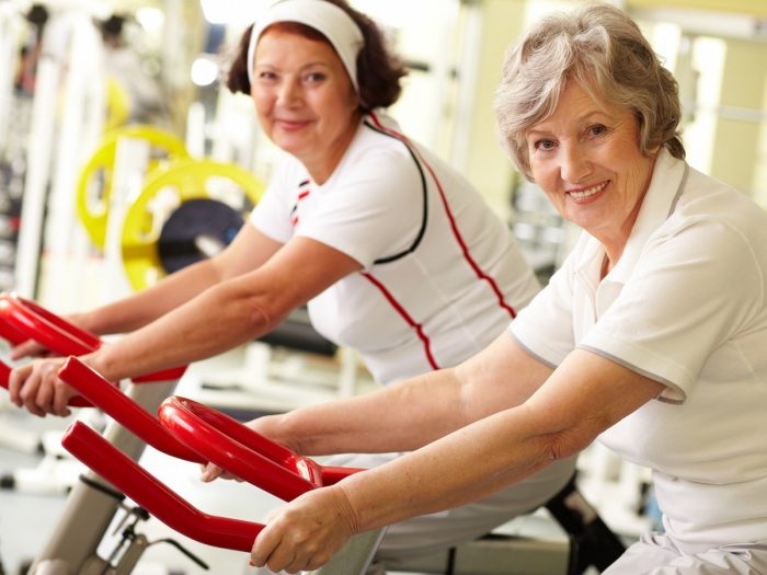 Two older women exercising in a gym