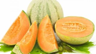 Whole and sliced cantaloupe melons with green leaves on a white background