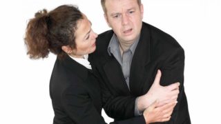 A man in a suit looking distressed, and a woman in a suit trying to help