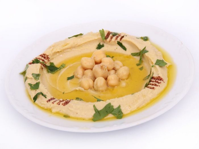 A plate containing hummus garnished with chickpeas and paprika