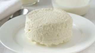 A white plate of cottage cheese on a white wooden table