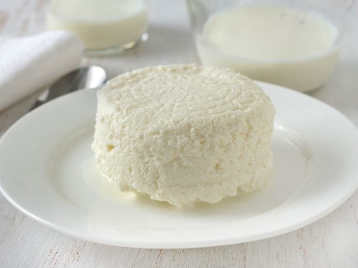 A white plate of cottage cheese on a white wooden table