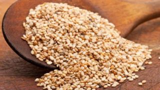 Organic white sesame seeds on the wooden spoon