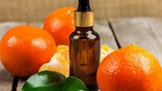 Mandarine essential oil bottle kept with few oranges aside