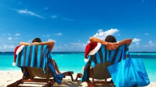 Two people sitting on a recliner at a beach