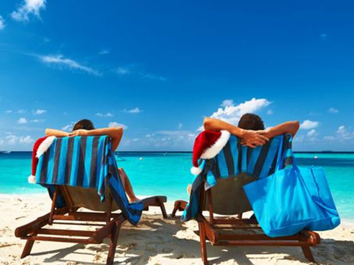 Two people sitting on a recliner at a beach