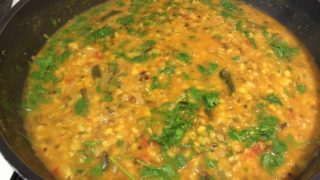 Organic mixed tadka dal in a saucepan, garnished with coriander leaves