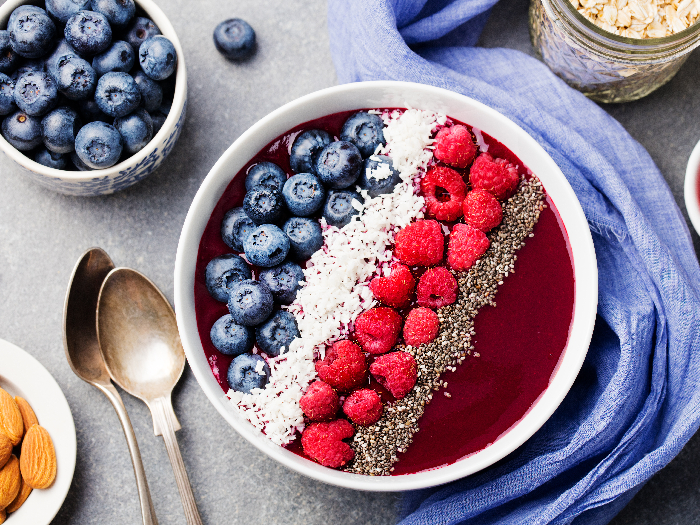 An acai bowl with fresh raspberry, blueberry, coconut flakes, and chia seeds