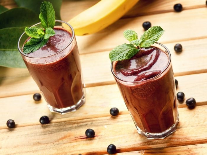 A close up shot of two glasses of acai berry juice kept atop a wooden table