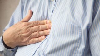 A man pressing against his chest while suffering from acidity