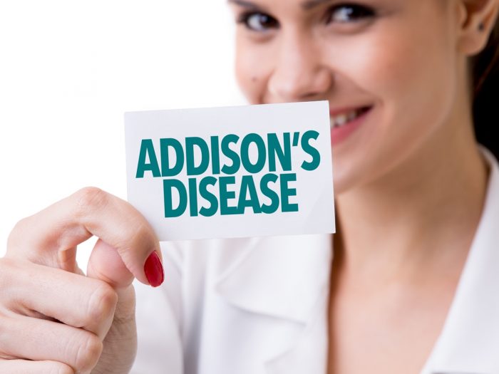 A woman holding a card that has Addison's disease written on it