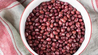 A white bowl of azuki beans on a wooden table