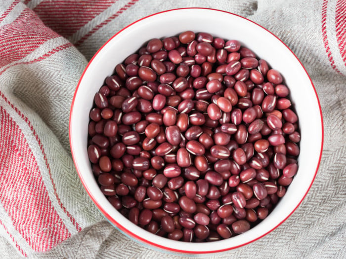 A white bowl of azuki beans on a wooden table