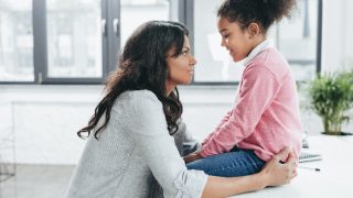 Side view of african american mother talking with her daughter indoors