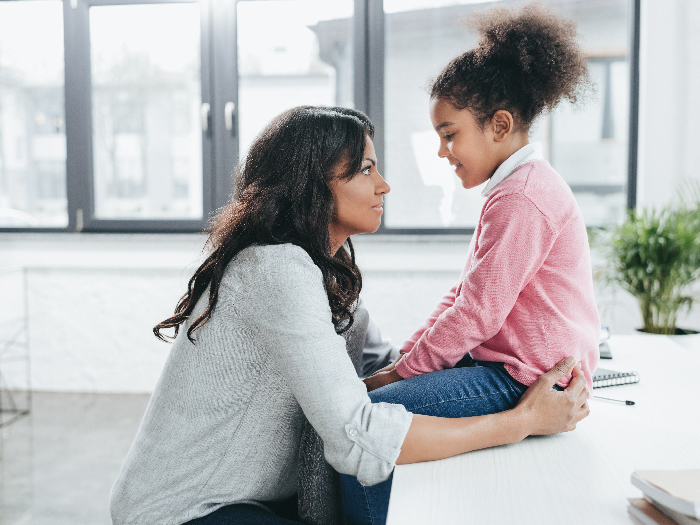 Side view of african american mother talking with her daughter indoors