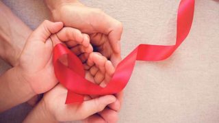 red aids ribbon help carefully by two pairs of hands