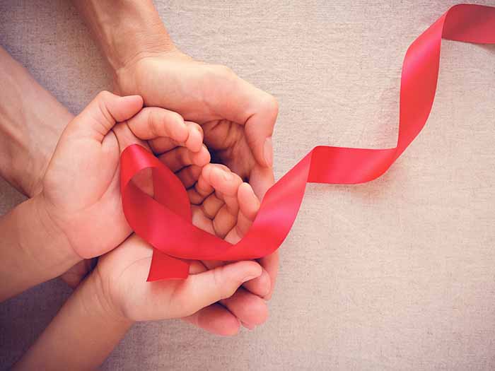 red aids ribbon help carefully by two pairs of hands