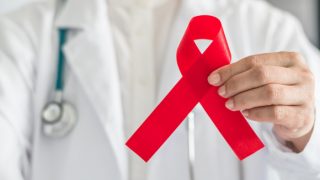 A doctor holding a red ribbon, the AIDS symbol