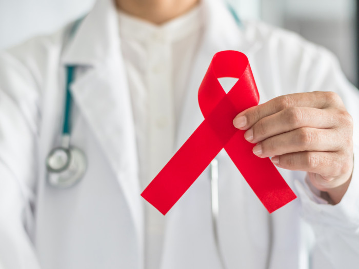 A doctor holding a red ribbon, the AIDS symbol