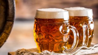 Two mugs full of ale on a cloth atop a wooden box