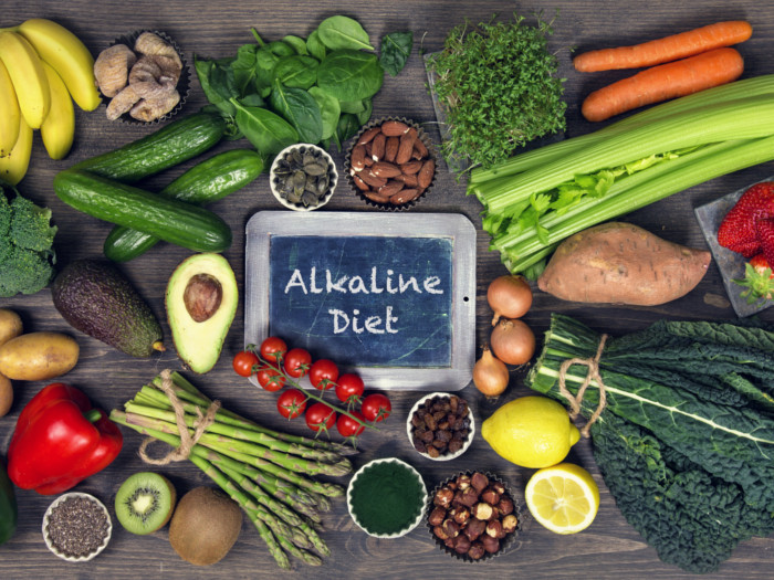 A flat-lay shot of various vegetables with a slate in between reading 'alkaline diet'