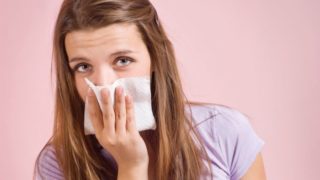A girl covering her nose and looking at the camera