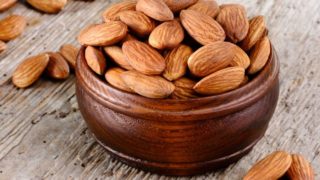 A bowl of almonds placed on a wooden table