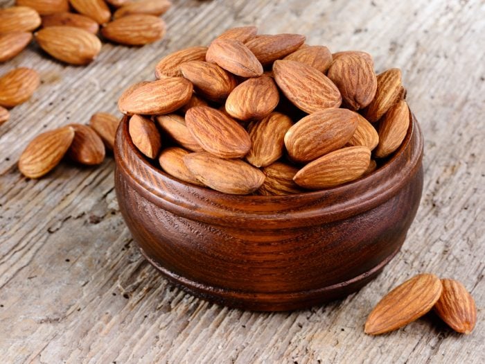 A bowl of almonds placed on a wooden table