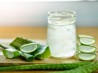 aloeverajuice Fresh aloe vera leaves and a glass of aloe vera juice on a wooden table