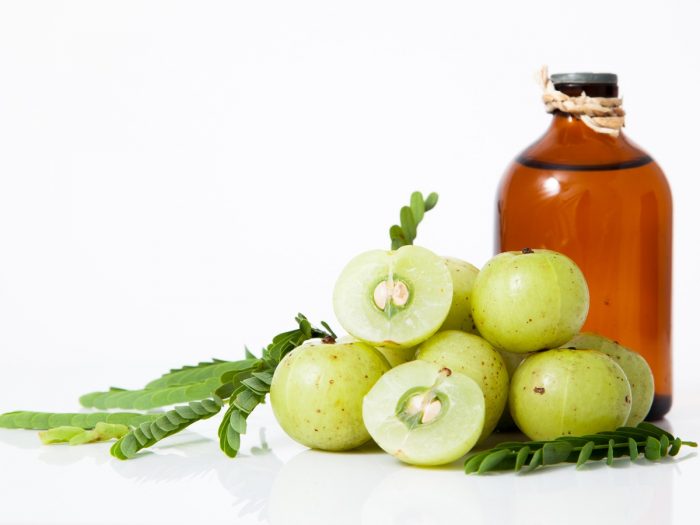 Shot of gooseberries with a bottle of oil at the back