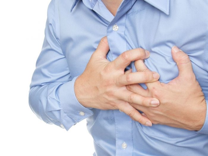 A young man suffering from angina symptoms holding his left side chest white background
