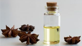 A bottle of star anise oil with star anise spice on the floor