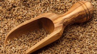 Close-up of anise seeds with a wooden scoop.