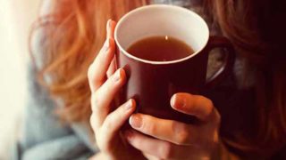 A girl wearing woolen holding a cup of tea in her hands