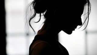 Silhouette of a woman's head with waving hair in a bun