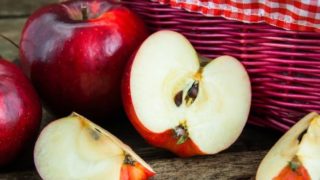 Cut apples kept next to a basket and whole apples atop a wooden platform