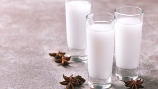 Three glasses filled with arak drink alongside star anise