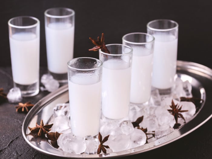 Arak served in shot glasses on a silver tray with star anise