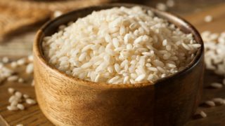 A bowl of arborio rice on a wooden table
