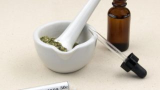 Bottle of arnica montana 30c and dried arnica leaves in a marble mortar